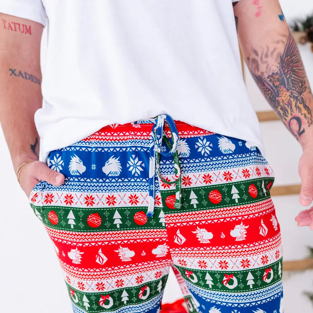 Close up of the drawstring waistband and pocket of jogger pajama pants in red, green, blue, and white fair isle stripes with snowflakes, pine trees, and white dragon heads.